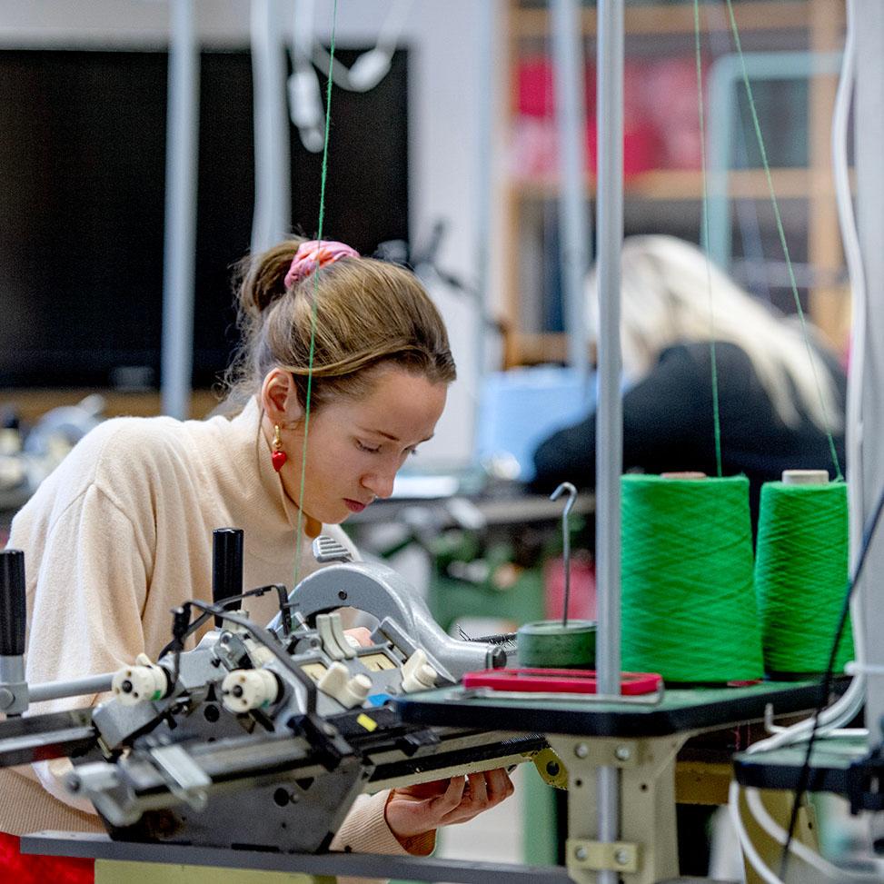 En kvinna sitter och syr vid en symaskin på Textilhögskolan.